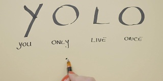 俯视图的女性手写励志引用yolo你只活一次与黑色钢笔和画在一张空白纸上的笑脸