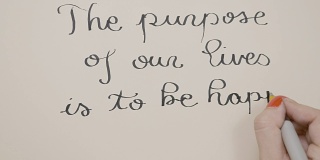 女性用黑墨水的笔在白纸上写下励志的信息，我们生活的目的是为了幸福