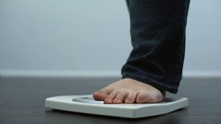 肥胖男性在磅秤上检查体重，健康失调，暴饮暴食结果视频素材模板下载