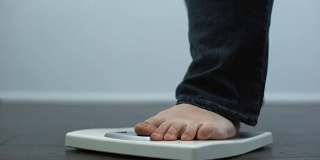 肥胖男性在磅秤上检查体重，健康失调，暴饮暴食结果
