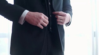 新郎穿着黑色西装，扣着上衣的扣子。视频素材模板下载