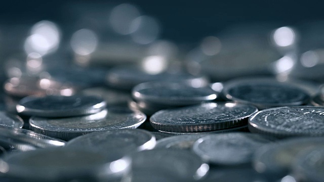 黑光下的硬币在地板上堆积的特写，商业和金融省钱或投资背景的概念，非常近，浅景深