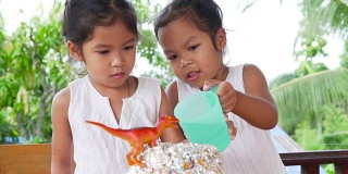 两个亚洲小女孩在自己家里的桌子上做小苏打和醋火山实验，慢镜头50帧/秒