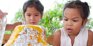 两个亚洲小女孩在自己家里的桌子上做小苏打和醋火山实验，慢镜头每秒100帧