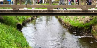 在大野Hakkai，人们走在宁静的河上的桥上，慢动作拍摄