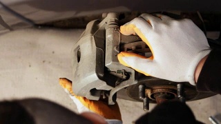 汽车修理工在一家汽车修理厂修理刹车。视频素材模板下载