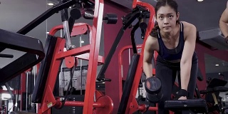 年轻的亚洲肌肉女性锻炼哑铃划船在健身房，生活方式运动和健美的概念