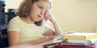 悲伤的女孩坐在一堆书的桌子旁。她揉了揉眼睛，想睡觉。学校教育的问题。回到学校