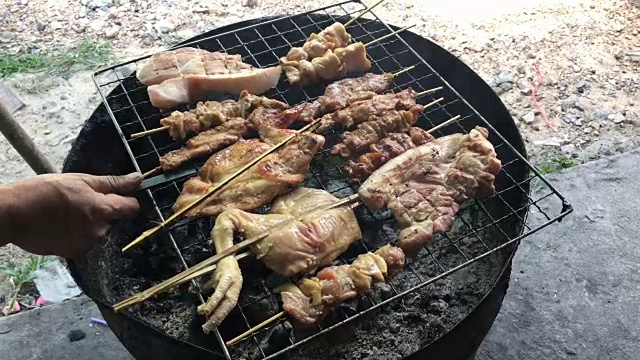 泰式街头小吃:炭火烤鸡，猪肉放在炉上半切油罐用烟熏。泰国风格的食物。泰式烧烤或“Moo Ping”在泰国字。4K视频
