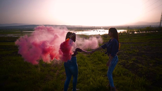 两名年轻女子拿着一枚粉色烟雾弹在空中转圈，慢镜头