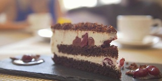 甜蜜的切成薄片的蛋糕，在咖啡馆的情侣面前聊天
