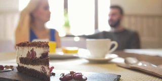在咖啡馆里，一对正在享用咖啡的夫妇面前，盘子里放着香甜的切成薄片的蛋糕