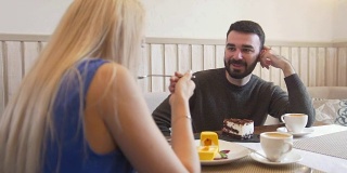 一个年轻的白人男人在咖啡厅里一个女人面前品尝甜点