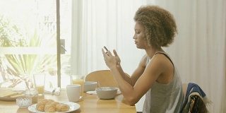 在早餐桌上用智能手机的美女