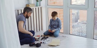 好奇的儿子和慈爱的父亲正忙着做木工，用工具和锤子钉钉子。父权与建构观念