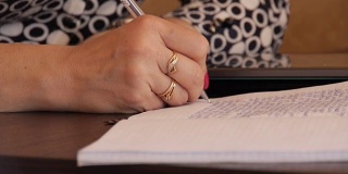 一位妇女用圆珠笔在笔记本上手写文字