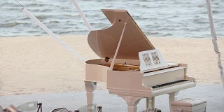 大钢琴以大海为背景，白色大钢琴站在沙滩上，婚礼在沙滩上举行，概念