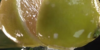 柠檬碰到橙汁表面，然后切成两半。慢动作镜头。近距离