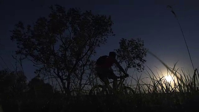 一个年轻人在日落时分积极地骑着自行车