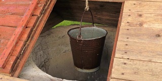 装满水的金属桶挂在农村的一口井里，滴水