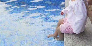 一个小女孩在度假村的游泳池里踢水。