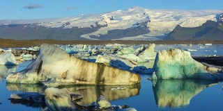 4k时间移动的云与蓝色冰山漂浮在Jokulsarlon冰湖，冰岛