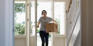 一名年轻女子在搬家当天搬运箱子进新家，用慢动作拍摄