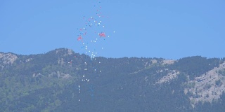 蓝、白、红三种颜色的气球在群山的映衬下升起
