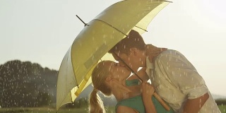 慢镜头:可爱的小情侣在清凉的夏雨中微笑和亲吻。