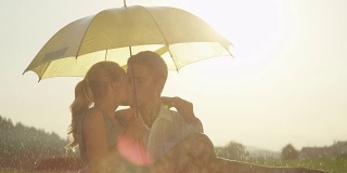 近距离特写:湿透的男人抱着他的女朋友，在雨中亲吻她。