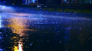 在城市的夜间道路上，汽车开进大水坑，车轮下溅起水坑视频素材模板下载