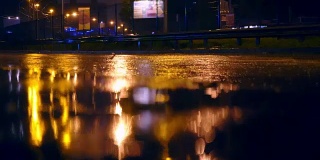 在城市的夜间道路上，汽车开进大水坑，车轮下溅起水坑
