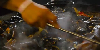 厨师在不锈钢锅里煎海鲜，煮牡蛎