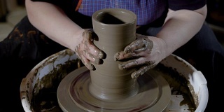 陶艺大师在作坊里用陶土在陶轮上塑造和成形花瓶的特写镜头