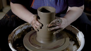 陶艺大师在作坊里用陶土在陶轮上塑造和成形花瓶的特写镜头视频素材模板下载