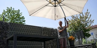 一个男人在阳台上撑开遮阳伞
