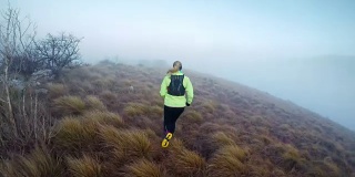 一个寒冷的早晨，一个女人在雾蒙蒙的山脊上跑步