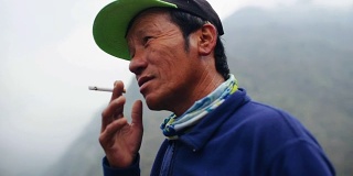 满脸皱纹的亚洲老头在户外抽烟
