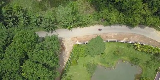 航拍:一名女游客正在探索通往一个泰国村庄的风景优美的道路。
