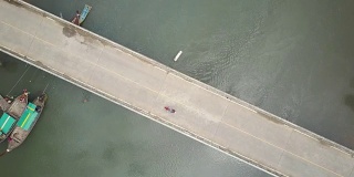 一名年轻女子骑着她的摩托车越过一座横跨热带河流的桥。