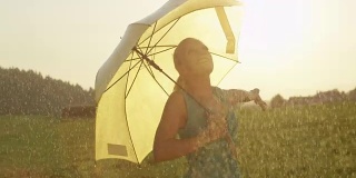 太阳耀斑:快乐的女人撑着一把黄色的伞，在春雨中旋转