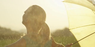慢镜头:无忧无虑的金发女郎让春雨落在她身上。