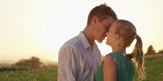 慢镜头:欢快的男人和女人在一次春雨中热吻。