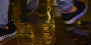 在雨天，人们的脚走过水坑，人们进入水坑