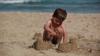 男孩正在海滩上建沙堡视频素材模板下载