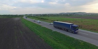 航拍卡车行驶在田野间的道路上。