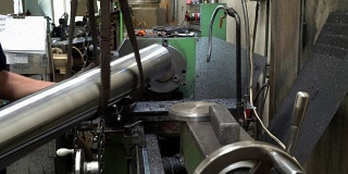 车床操作工把金属管从机器上移下来。