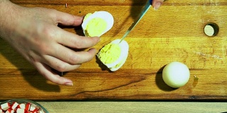 厨师在黄色的厨房板上用刀工作。煮鸡蛋。