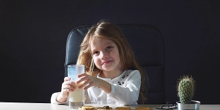快乐美丽的小女孩正在吃牛奶和饼干