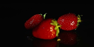 三颗草莓躺在深色的背景上